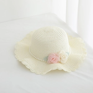 Detail of children's straw hat with pearl trim, fabric roses and scalloped wavy brim