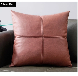 Detail of cinnabar red faux leather pillow cover with decorative cross-stitch on a sofa