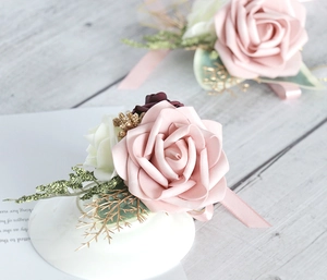 Detailed view of artificial wedding corsages with soft pink roses and gold leaf accents