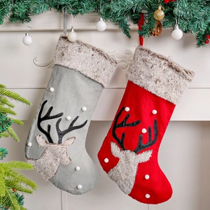 Hanging plush reindeer Christmas stockings in red and grey colors by a cozy fireplace