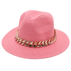 Gros plan du chapeau fedora en paille rose avec une chaîne décorative en métal doré