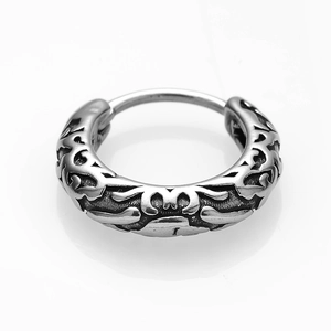 Detailed close-up of silver stainless steel earring with intricate tribal pattern carving
