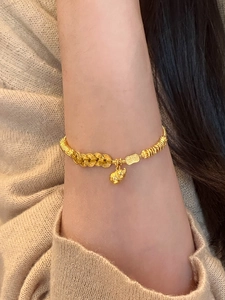 Close-up of golden gourd bracelet with ancient coin links on a female wrist