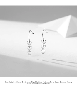 Detailed view of silver heart-shaped tiered drop earrings with a polished finish