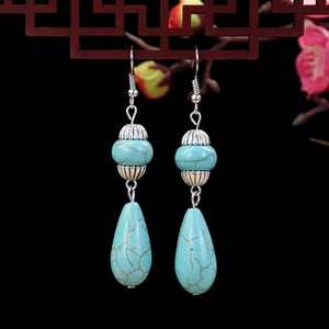 Close-up of vintage turquoise drop earrings with silver flower spacers on wooden decor
