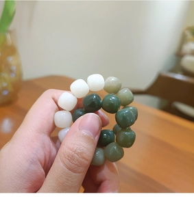 Detail of beaded hair tie with gradient green cubic beads held in hand for texture