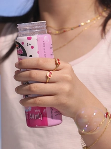 Vue détaillée de deux bagues papillon dorées avec finition pailletée rouge éclatante