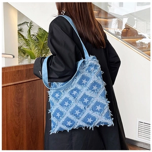 Detailed view of the denim shoulder tote bag with star patchwork on a model back
