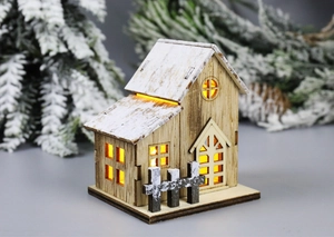 Dettaglio di una casa di Natale in legno con finestre a LED luminose e un effetto neve realistico
