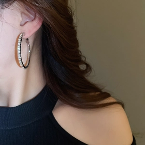 Close-up of sparkling silver hoop earrings with pavé rhinestones worn by a model