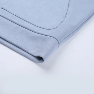 Detail of light blue jacket showing kangaroo pocket stitching and smooth fabric texture