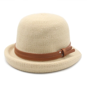 Detailed view of beige knitted fedora featuring a brown leather strap and metal studs