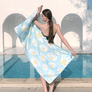 Light blue microfiber beach towel featuring white daisy patterns displayed by pool