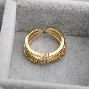 Adjustable golden geometric open ring with cubic zirconia on a gray jewelry box display