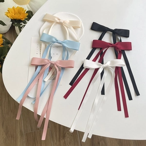 Flat lay of colorful double-layered ribbon bow hair clips with long flowing streamers