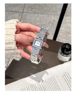 Détail de la montre carrée argentée avec cadran à motif et bracelet métallique