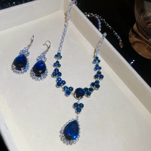 Macro shot of silver zircon flower jewelry set with dark blue teardrop pendants