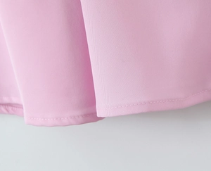 Dettaglio macro delle cuciture precise e dell'orlo su un abito rosa con spacco in tessuto