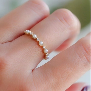 Elegant gold ring featuring freshwater pearls and accent diamonds on a model's finger