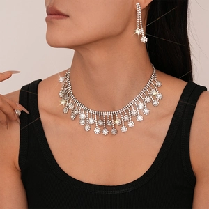 Détail de l'ensemble élégant de boucles d'oreilles fleurs à pompons et collier diamant