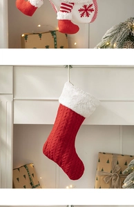 Detailed view of red knitted Christmas stocking with plush cuff hung by a fireplace