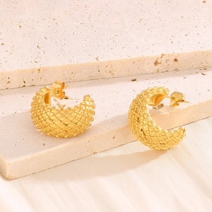 French vintage C-shape gold earrings with unique granular texture on a stone pedestal