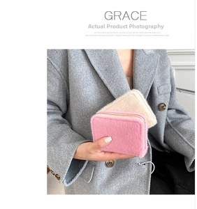 Nahaufnahme von flauschigen Kunstfell-Geldbeuteln in Pink und Beige mit Goldreißverschluss