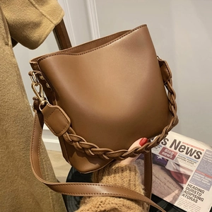 Brown faux leather bucket bag with woven handle and adjustable strap for women