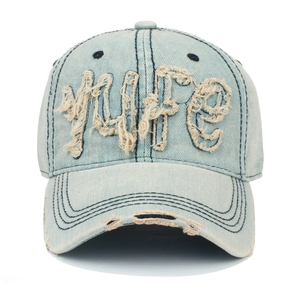 Détail de la broderie effilochée sur une casquette de baseball en jean délavé usé