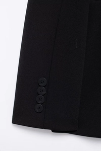 Detail of black blazer sleeve cuff with four matching buttons and textured fabric finish