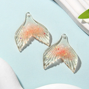 Detailed view of resin mermaid tails with pink and gold glitter for DIY jewelry making