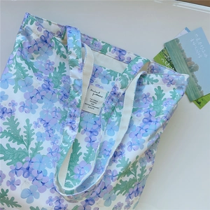Vue détaillée du sac cabas en toile avec motifs floraux et poignées tissées