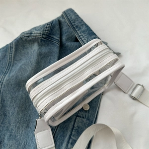 White clear PVC crossbody bag with wide strap placed on denim jacket, fashion style