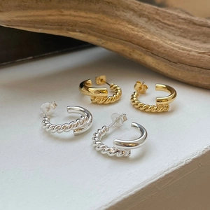 Detail view of gold and silver S925 sterling silver woven C-shaped stud earrings