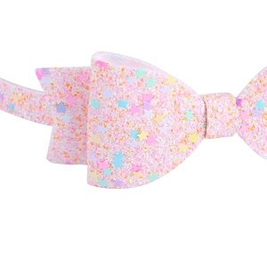 Détail macro du nœud à cheveux rose pailleté avec sequins étoilés colorés et fini scintillant