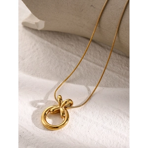 Detail of 18k gold plated stainless steel necklace with XO circle pendant on a textured background