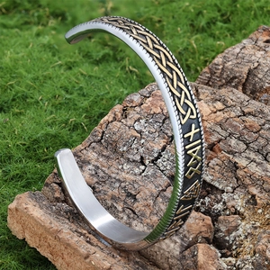 Macro detail of silver and gold Viking cuff bracelet with Celtic knots on tree bark