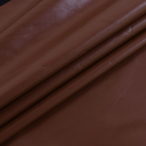 Dettaglio macro del tessuto in ecopelle marrone che mostra texture morbida e grana fine