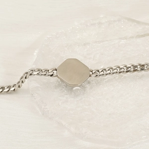 Polished silver cuban link bracelet for men with hexagonal metal plate on glass tray