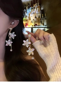 Detail view of flower tassel earrings with pearls and crystals worn by a model