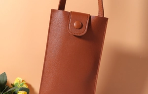 Detail of caramel brown leather phone bag with fine stitching and snap button closure