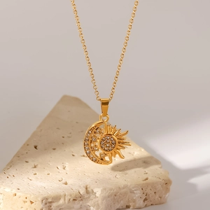 Detail of gold sun and moon pendant with sparkling crystals on minimalist stone base