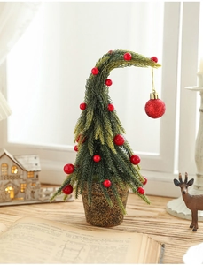 Close-up of a mini snowy Christmas tree with red berries in a brown pot