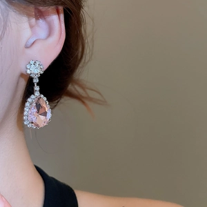 Close-up of pink teardrop crystal earring with small diamonds on silver metal base