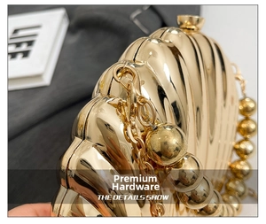 Detail of a golden shell-shaped evening bag with polished metallic texture and beaded chain