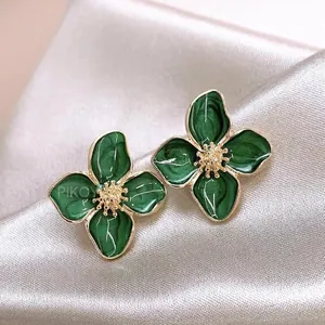 Retro flower earrings with dark green enamel petals and gold accents on champagne silk