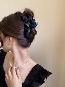 Dettaglio elegante molletta per capelli a fiocco in raso nero con ricamo su un'acconciatura