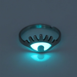 Macro shot of luminous eye-shaped ring glowing blue-green in dark with clear reflection