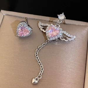 Macro detail of silver asymmetric heart earrings with pink zircon and long chain tassels