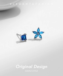 Detail of asymmetric S925 silver earrings with blue square gem and flower design